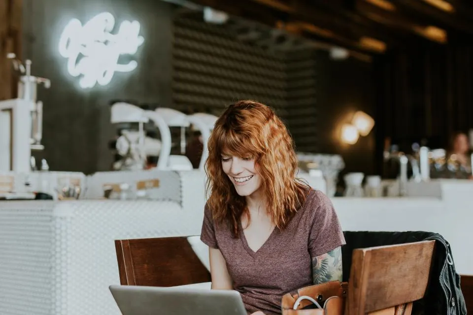 Mujer sonriente estudiando con un portátil